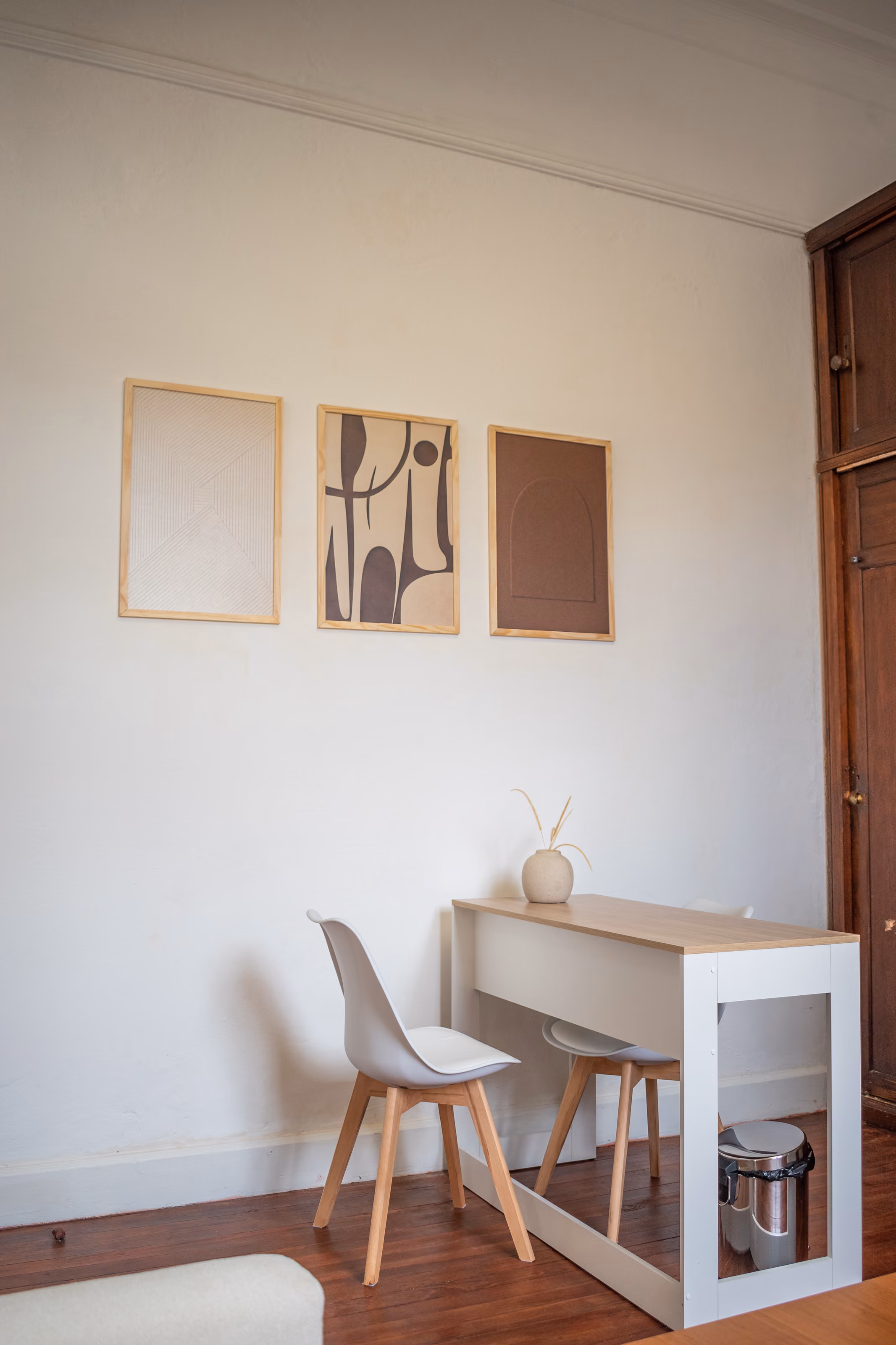 Consultorio 01: el escritorio con su silla, bajo tres láminas enmarcadas en madera clara.