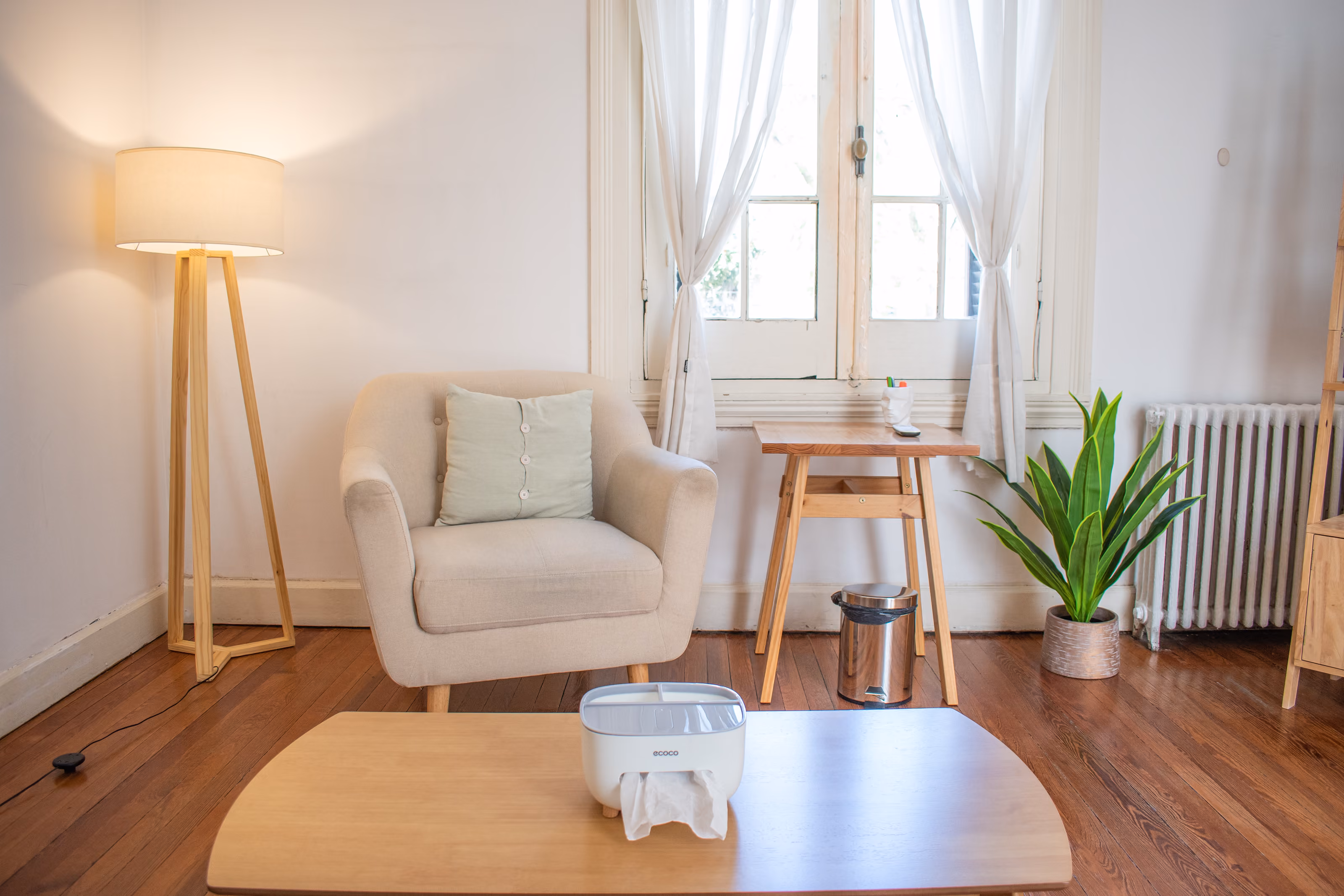 Consultorio 02: el sillón de atención, la mesa baja y el escritorio junto a la ventana con cortina de voile.