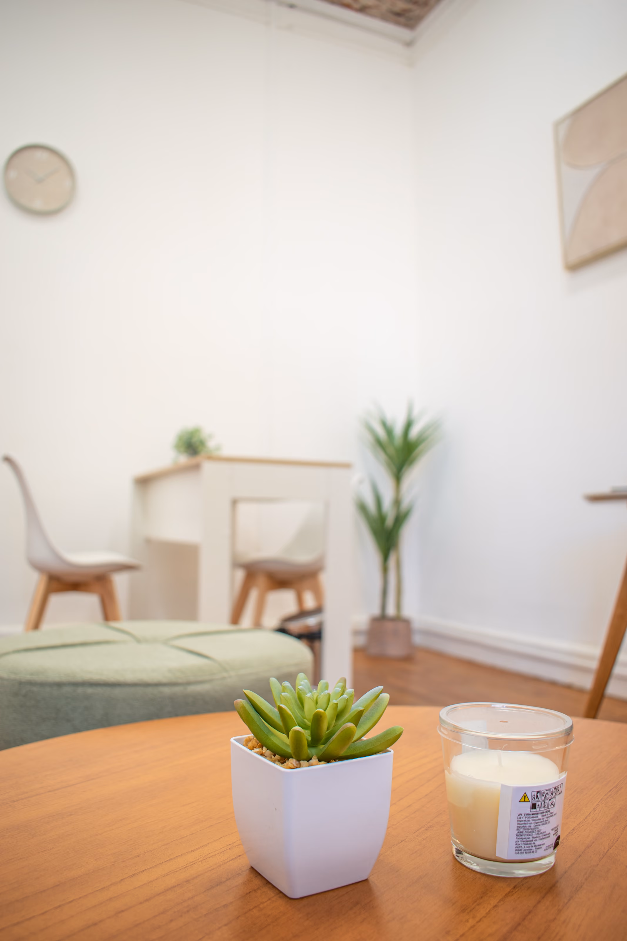 Consultorio 03: una vela y una planta pequeña sobre la mesa baja, con el escritorio desenfocado al fondo.