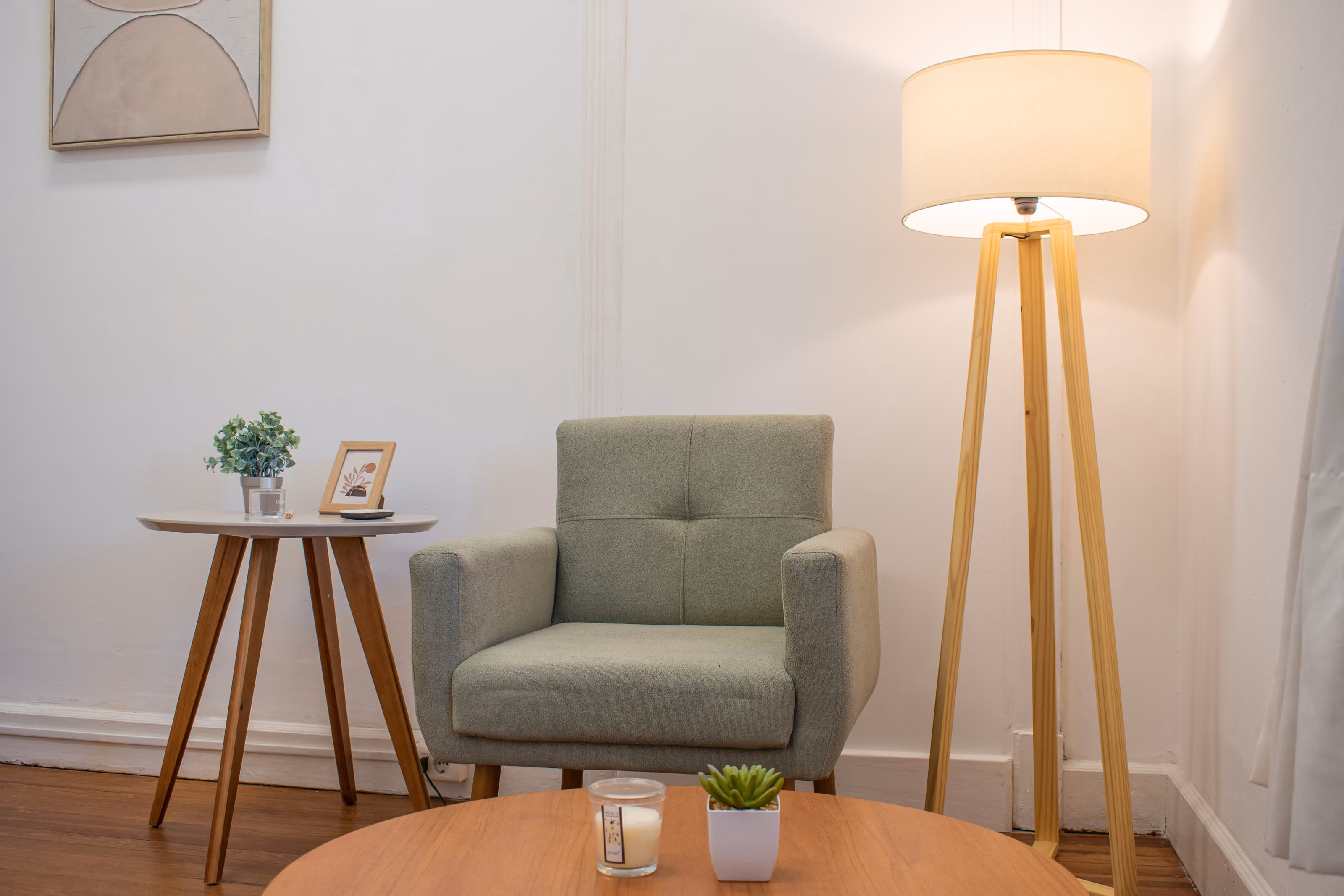 Consultorio de Espacio Luma con sillón verde, lámpara de pie de trípode encendida y una mesa auxiliar con plantas.